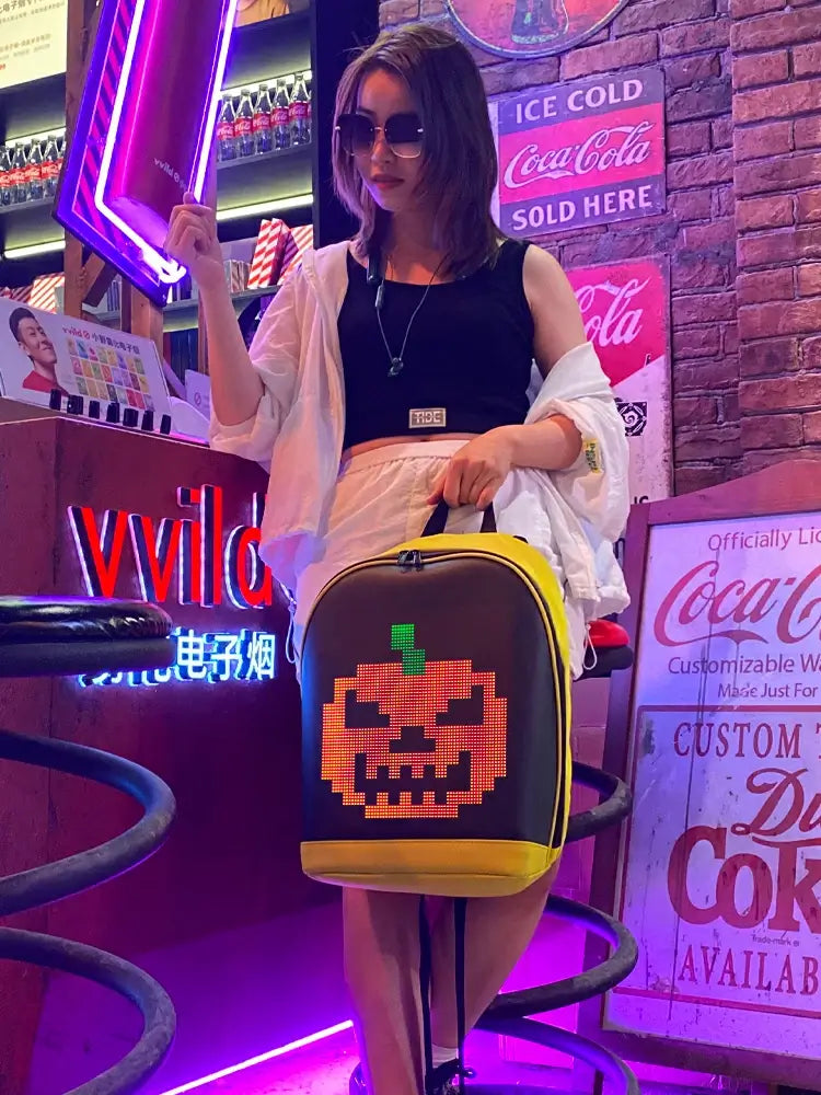 Stylish woman holding Gelrova T2 LED Backpack with a pumpkin design in a vibrant neon-lit setting.