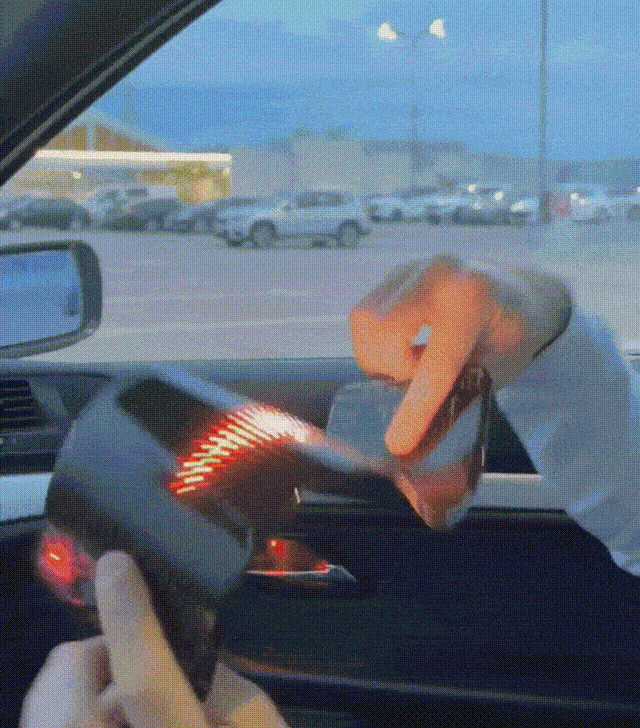 Person showcasing the Gelrova Customizable Car LED Display with vibrant animations in a car.