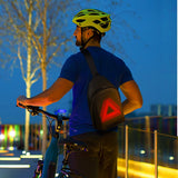 A person riding a bike, carrying the LED Crossbody Bag – City Series
